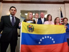 A group of people posing with a venezuelan flag.