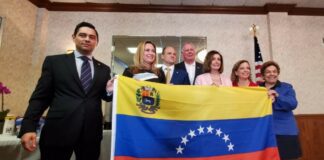 A group of people posing with a venezuelan flag.