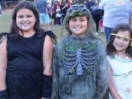 Three girls dressed up in costumes at a halloween event.