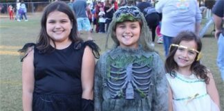 Three girls dressed up in costumes at a halloween event.