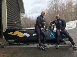two people leaning on a bobsled