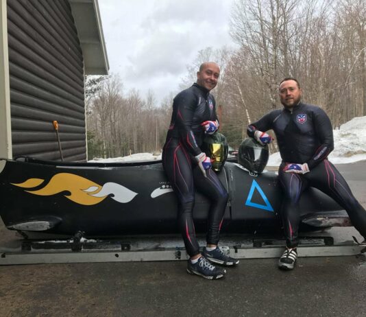 two people leaning on a bobsled