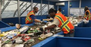 Two men sorting through garbage on a conveyor belt
