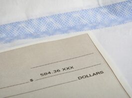 A check is sitting on top of a sheet of paper.