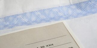 A check is sitting on top of a sheet of paper.