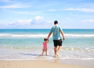 man walking with baby on beach