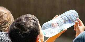 A boy is drinking water from a plastic bottle.