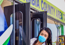 A woman wearing a face mask gets on a bus.