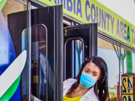 A woman wearing a face mask gets on a bus.