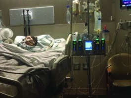 A woman is lying in a hospital bed with a monitor.