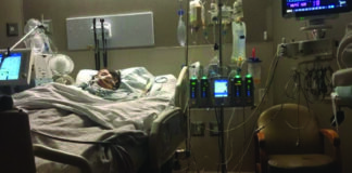 A woman is lying in a hospital bed with a monitor.