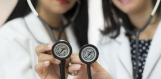 Two female doctors holding stethoscopes.