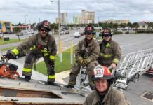 A group of firefighters standing on top of a ladder.