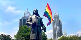 Rainbow flag behind statue in Mobile Alabama