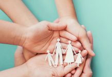 Multiple hands holding a cutout of a family