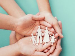 Multiple hands holding a cutout of a family