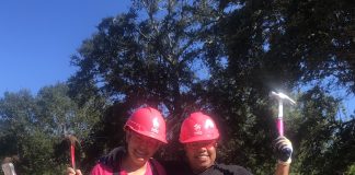 Two women wearing pink hats and hard hats.