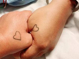 two hands with heart shaped tattoos
