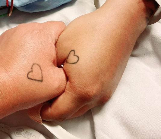 two hands with heart shaped tattoos