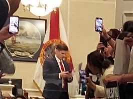 A group of people sitting on the floor holding phones.