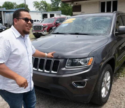 Antonio Estaba displaying a jeep on his dealership lot