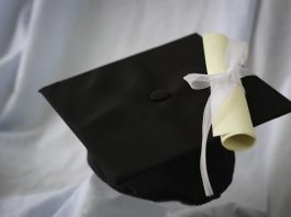 A black graduation cap and diploma on a white background.
