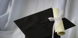 A black graduation cap and diploma on a white background.