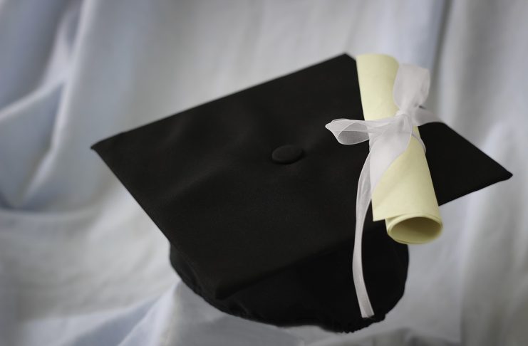 A black graduation cap and diploma on a white background.