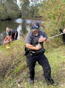 County employee holds duck with arrow pierced through its side.