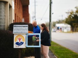 Two people stocking a community little library