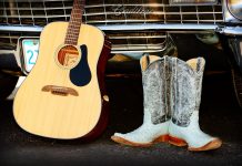 Guitar and cowboy boots leaning against a car grill