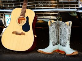 Guitar and cowboy boots leaning against a car grill