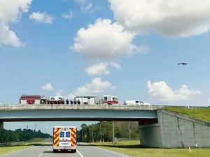 First Responders line up on overpass, helicopter flying over. 