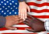 multi ethnic hands touching US flag