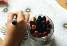 Child's hands creating art with crayons