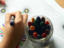 Child's hands creating art with crayons