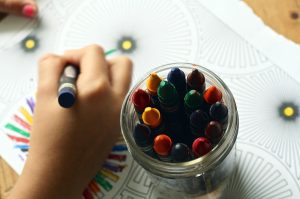 Child's hands creating art with crayons