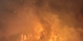 Car parked in front of a house that is in flames