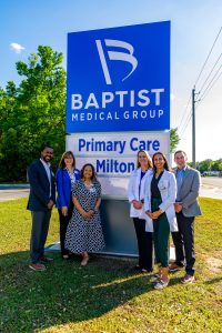 People standing next to the Baptist medical facility sign