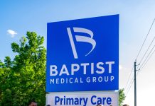 People standing next to the Baptist medical facility sign