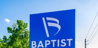 People standing next to the Baptist medical facility sign
