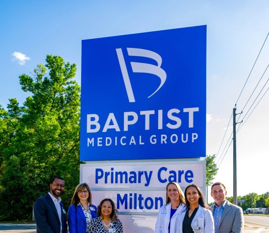 People standing next to the Baptist medical facility sign