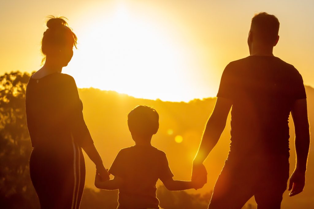 Silhouette of family walking toward the sun.