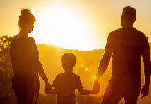 Silhouette of family walking toward the sun.