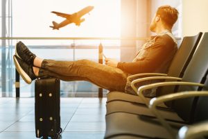 Man sitting at airport watching a plane fly