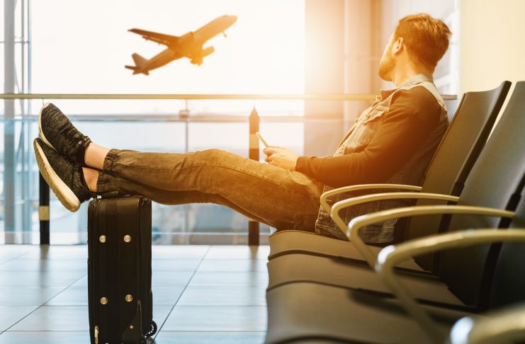 Man sitting at airport watching a plane fly